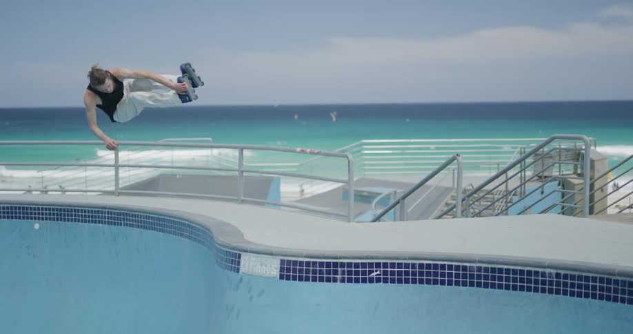 Young man roller skates inside empty pool near the beach at day