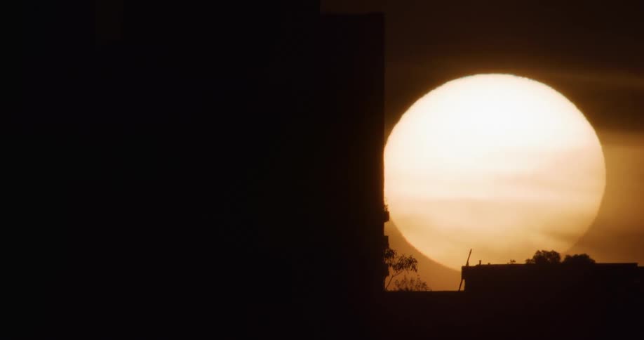 Golden big sun sets over city buildings