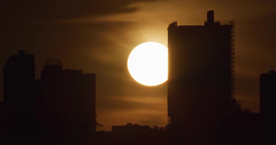 The sun sets behind the building