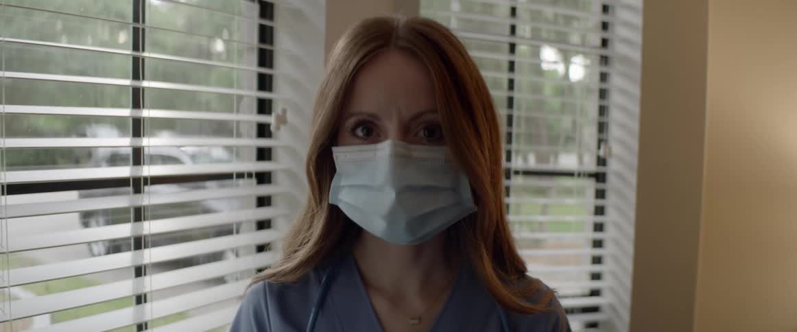 Female doctor looking down at the ground raises her head and stares at the camera in the clinic