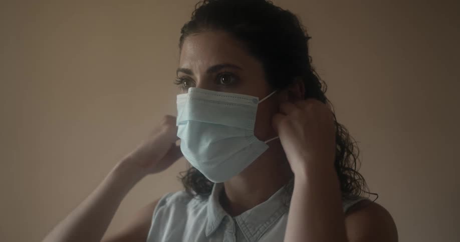 Woman reaches up and removes face mask