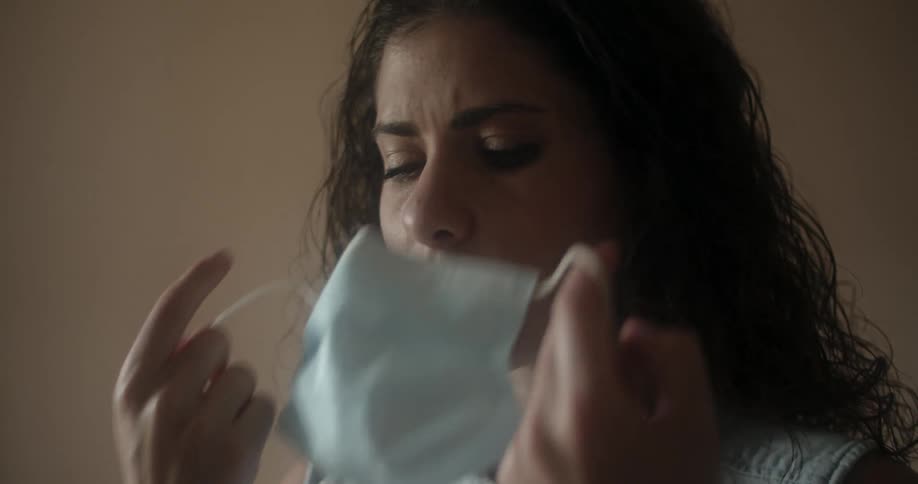 A woman removes her face mask and walks out of the room