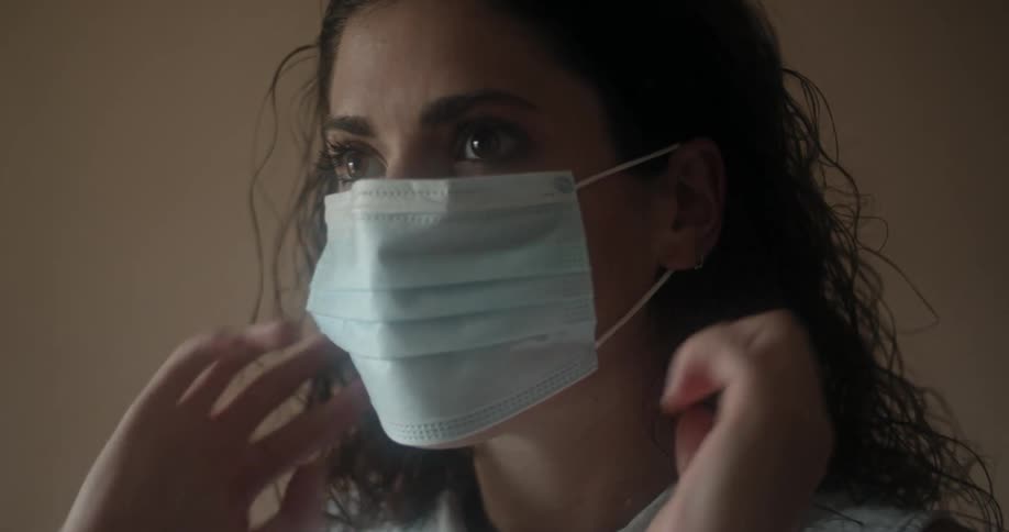 A woman puts on a disposable face mask