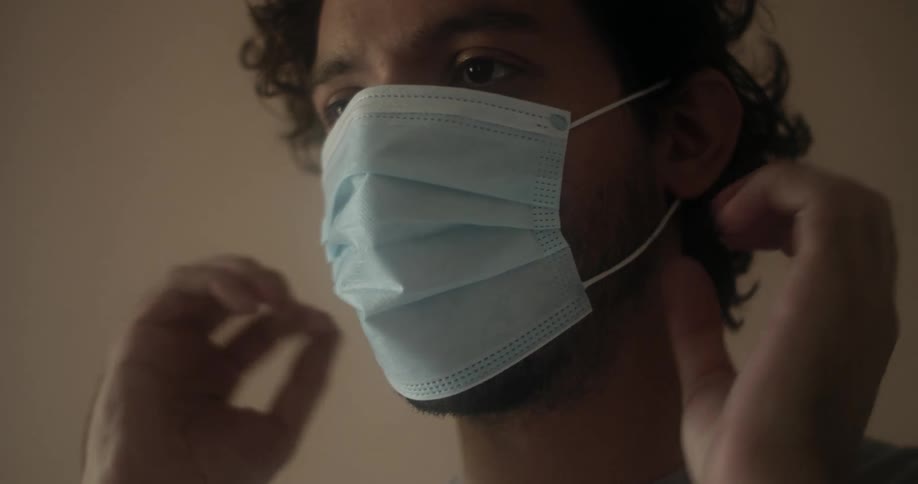 Man puts on face mask and adjusts it