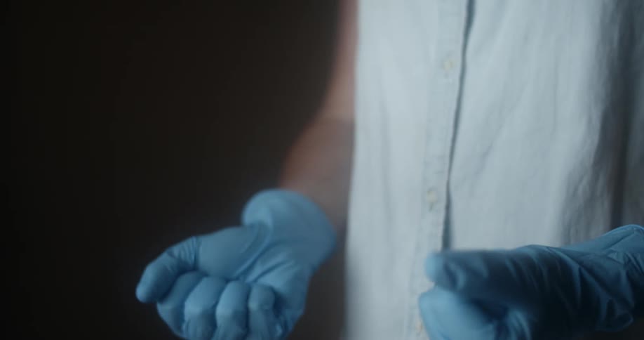 A woman demonstrates how to check the fit of a pair of blue latex gloves