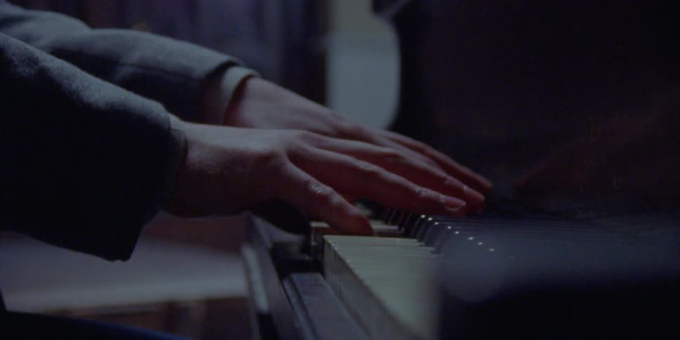 Man plays the piano while wearing suit jacket