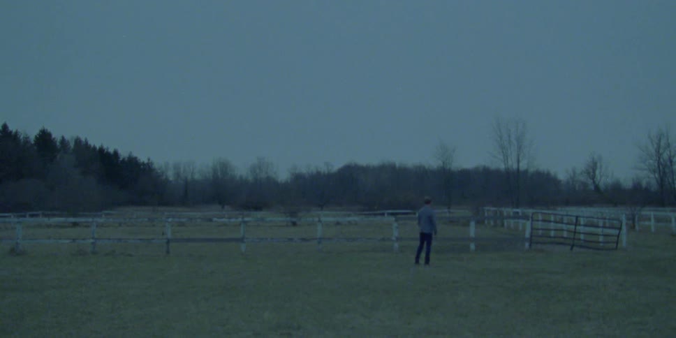 A man stands on an open ranch and looks around