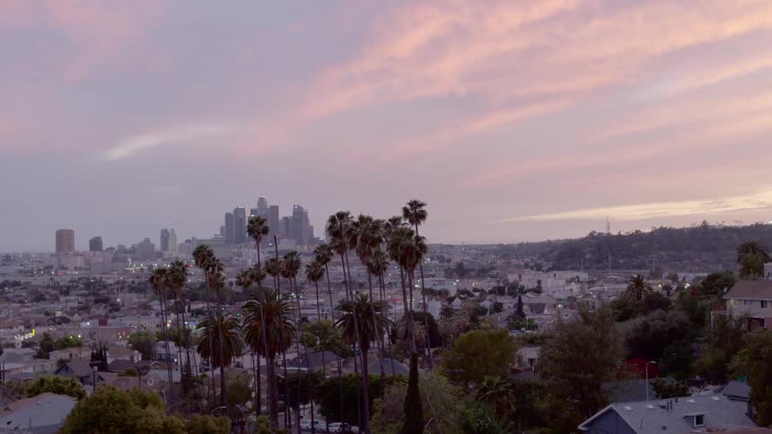 The sun sets over a neighborhood with downtown visible in the distance