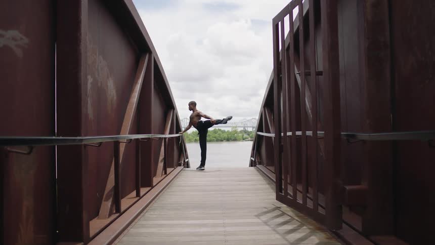 A man is stretching outdoors on a bridge