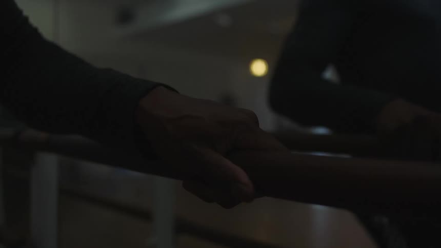 A ballet dancers hand gripping the bar and reflected in the mirror of a dance studio
