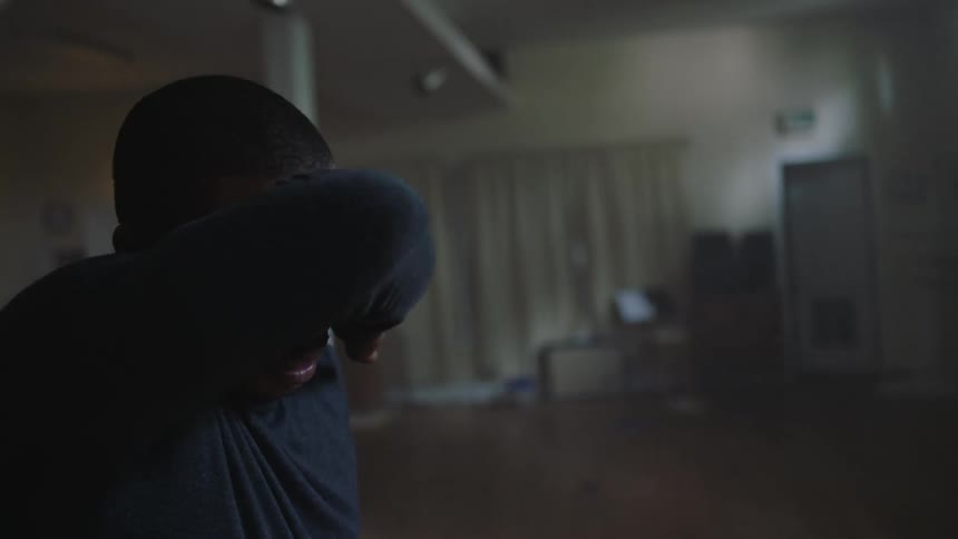 A man standing inside wiping sweat off his face