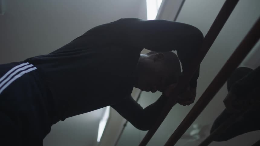 Man rests and leans against the ropes in a gym