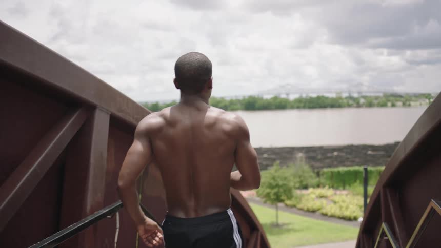 A man runs and stops before a lake
