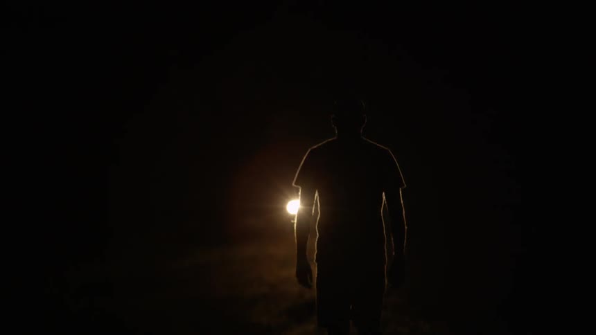 Man walking towards light at night