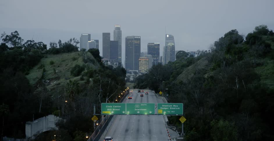 Cars driving down a highway to Los Angeles at dawn