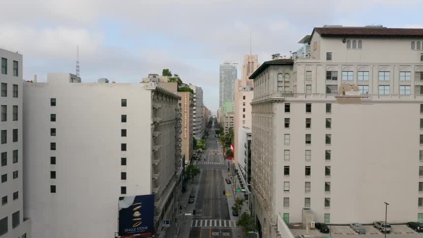 A street lined with tall buildings running through a metropolis during the day