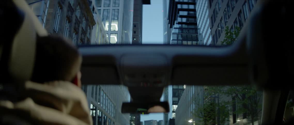 Man drives down the street surrounded by tall buildings in the city