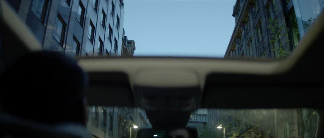 A man driving with his reflection in the rearview mirror and the sunroof opened