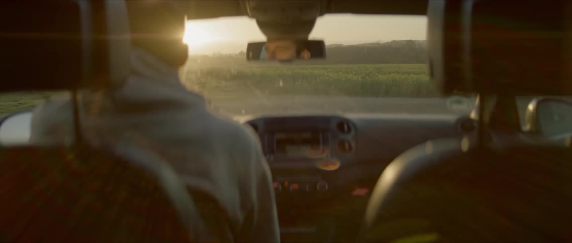 A man driving a car with his reflection in the rearview mirror