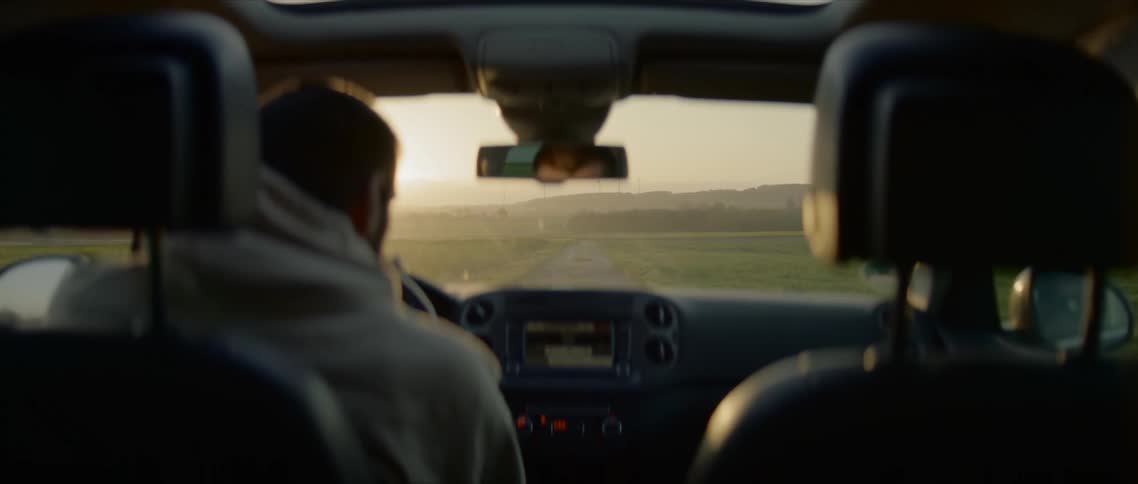 A man driving his car looks out the passenger window