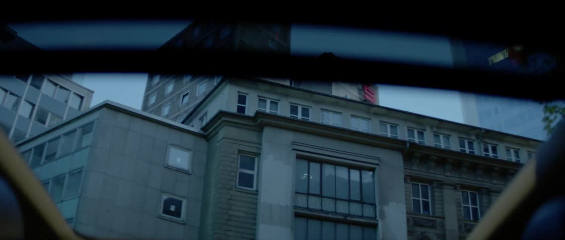 A car makes a turn by the tall building