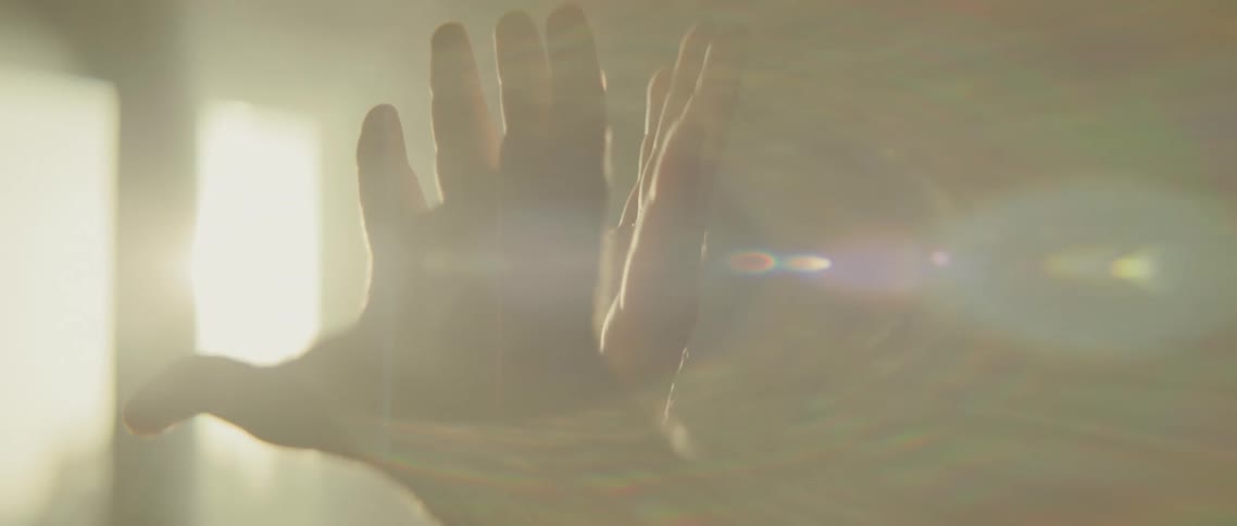 A man stands in front of a window and raises his hands in the air