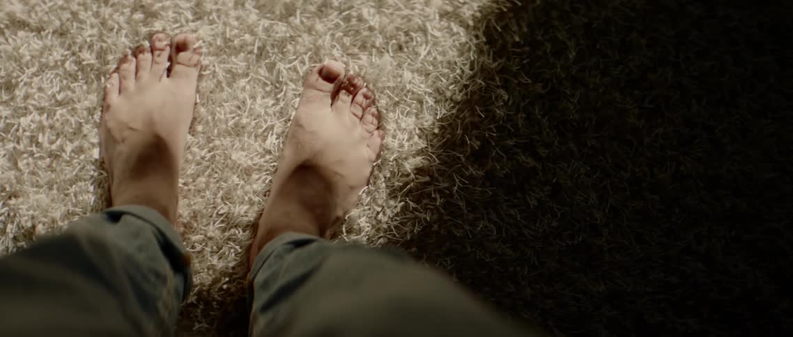 A persons feet standing on a carpet with sunlight shining on it
