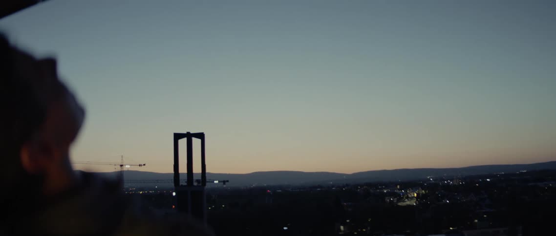 A person laying down on a roof with buildings in the background