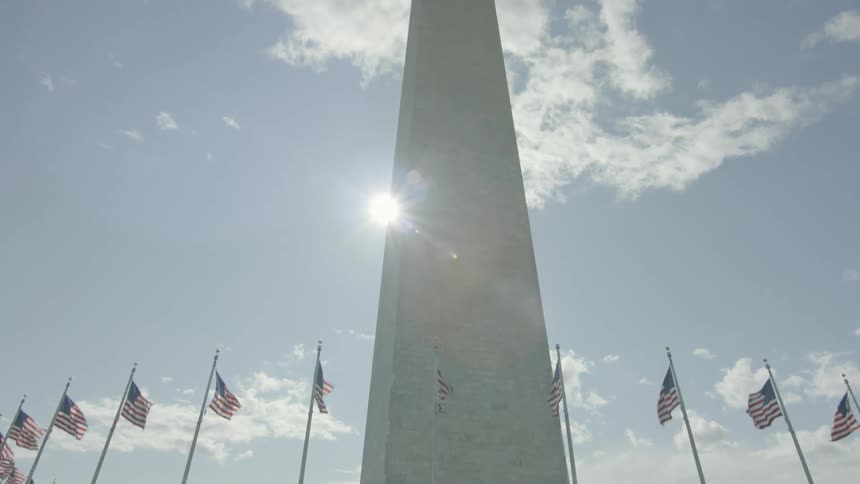 A tall monument is surrounded by american flags