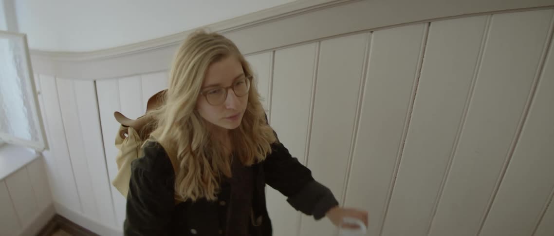 A teenager takes off her mask as she walks upstairs