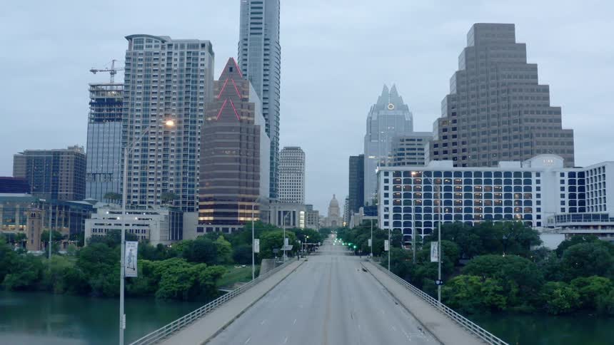 A vehicle driving on a bridge with buildings and skyscrapers in the background