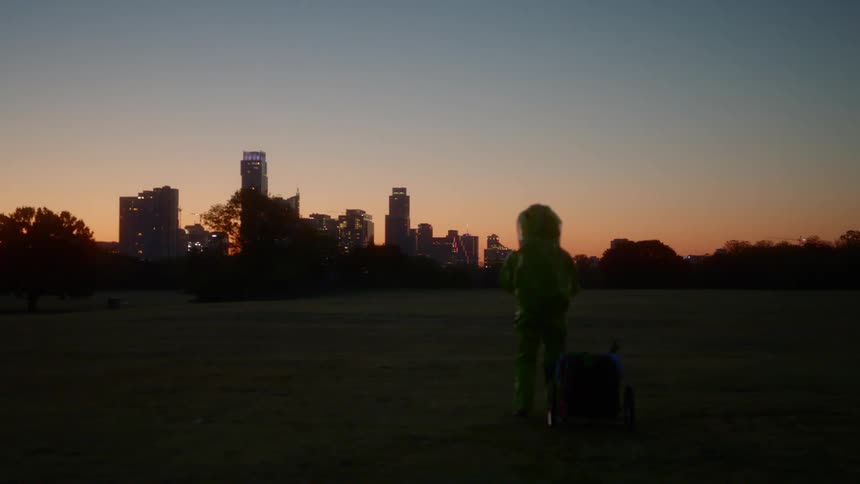 A man wearing protective gear stands and looks towards the city skyline