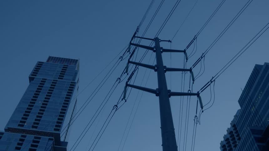 Power lines on a pole against the sky with city buildings behind