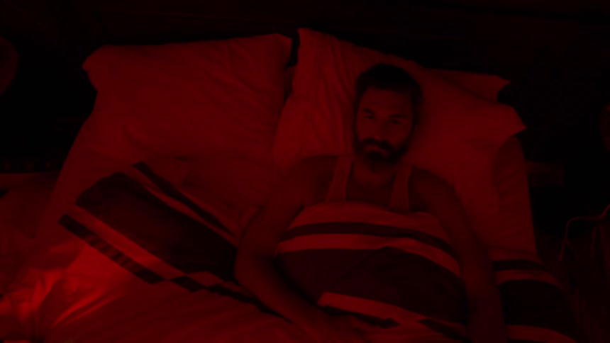 A man lies in bed in the dark