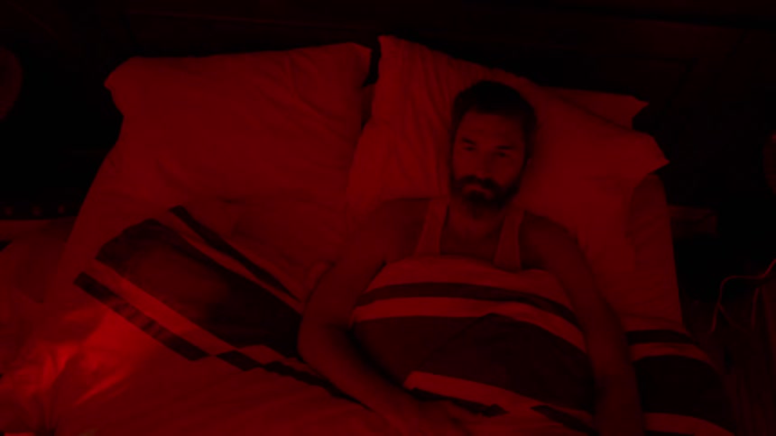 A man lays in bed with a red light shining