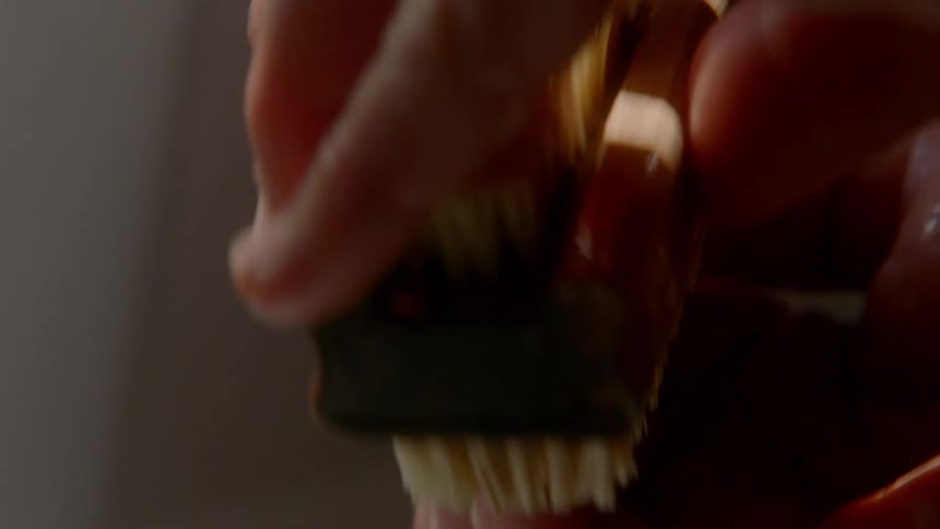 A man scrubs his nails with a nail brush