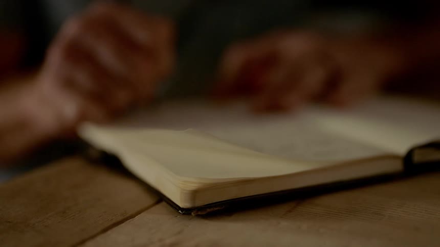 A mans hand writing in a notebook