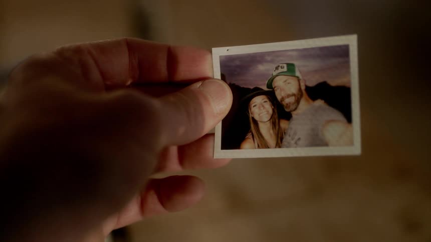A man looks at a photograph of a man and woman smiling
