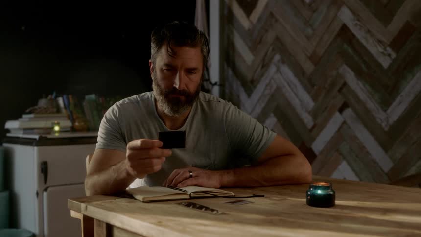 A man is sitting at a table and reading a book
