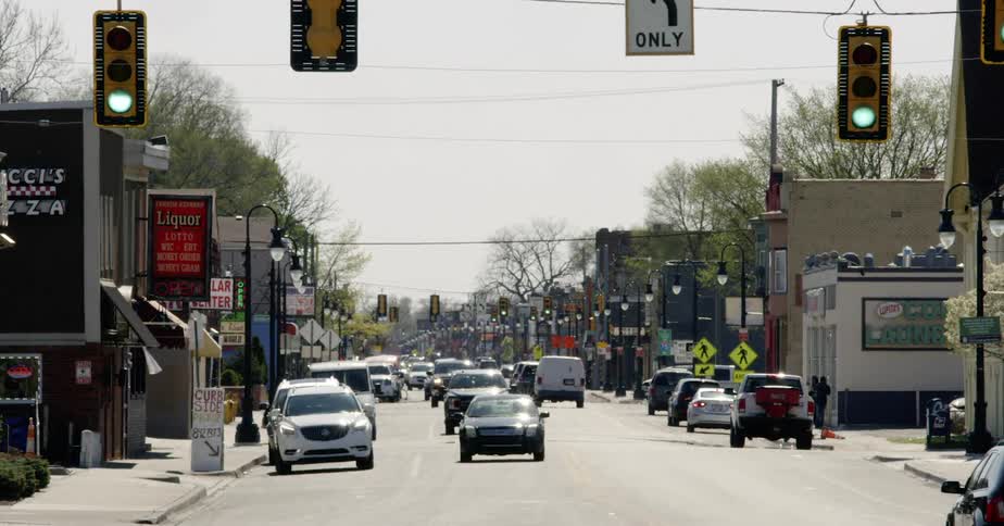 Curbside pickup sign as Cars drive along road between businesses