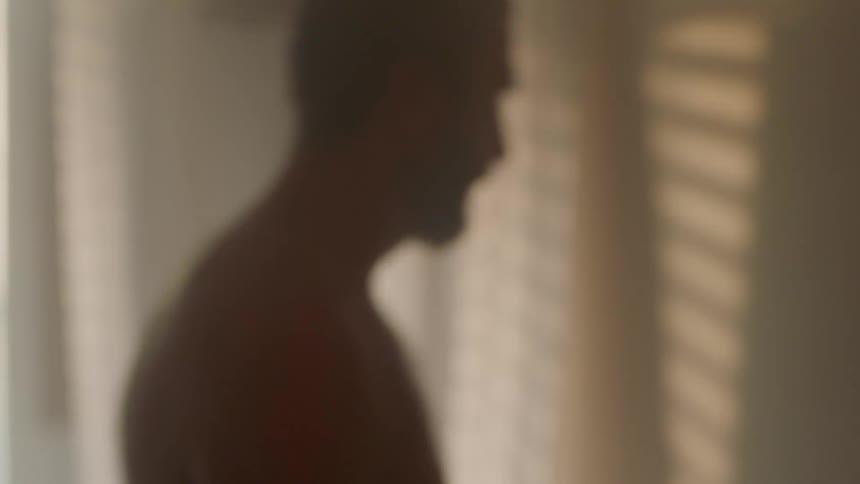 Bare chested man paces back and forth in room withsunlight casting shadows