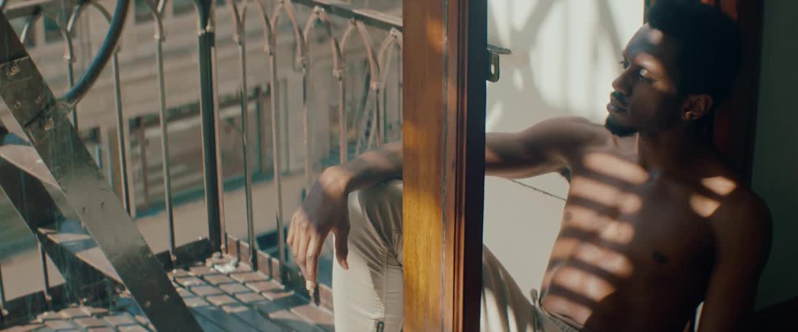 Shirtless black man sit in the apartment balcony