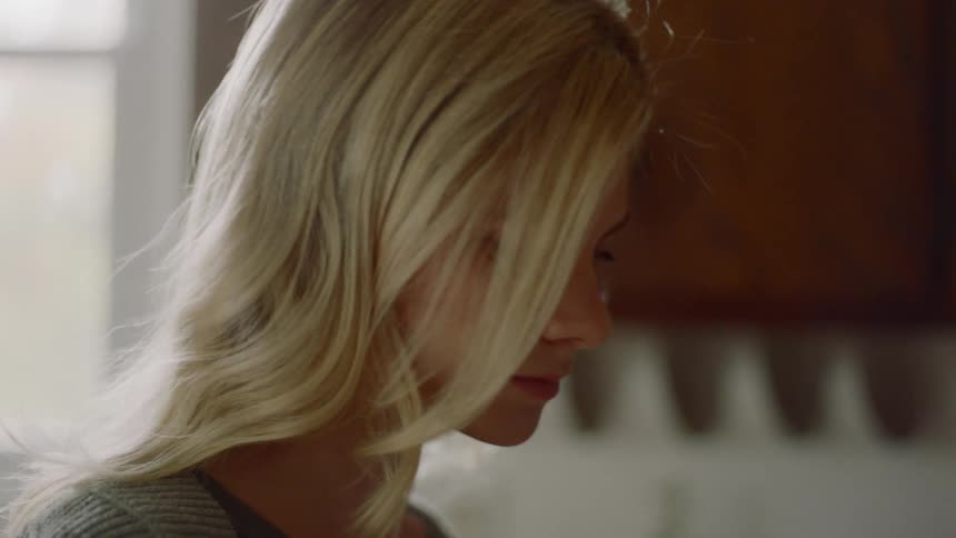 A young woman walking forward and stopping to examine something off screen