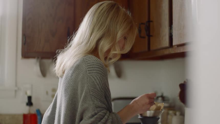 A woman makes coffee at home
