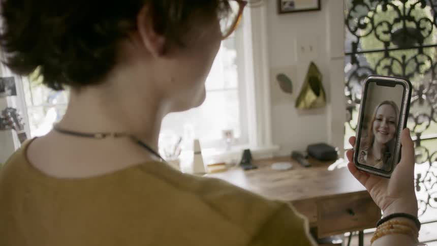 A woman talks to her friend via video call on her smart phone