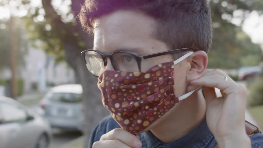 Male adjusting mask outdoors
