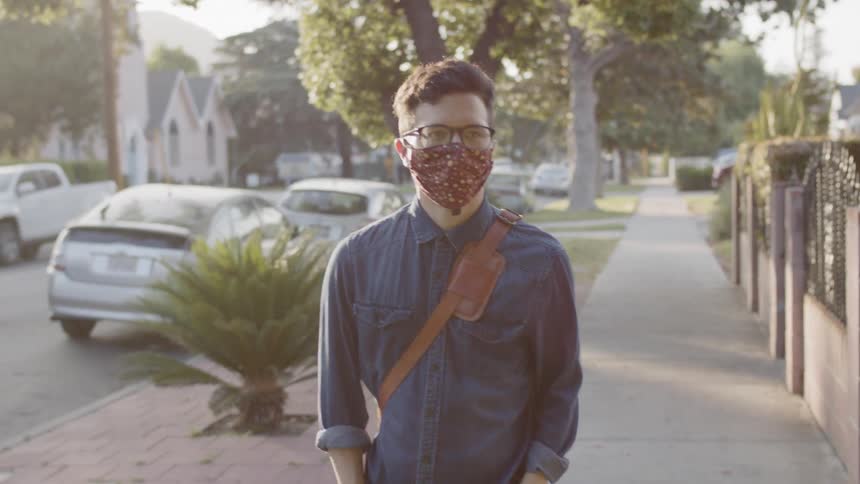 A man walking down the sidewalk with a mask on