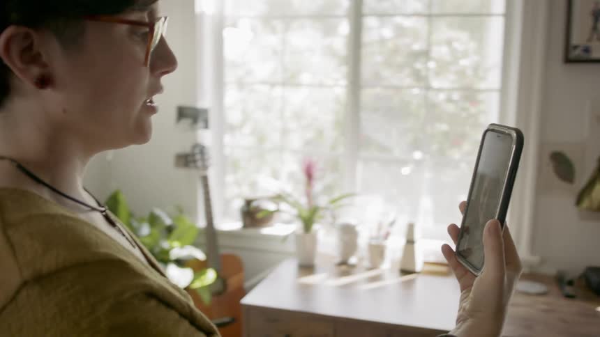 Woman greets young girl in video call on smartphone at home
