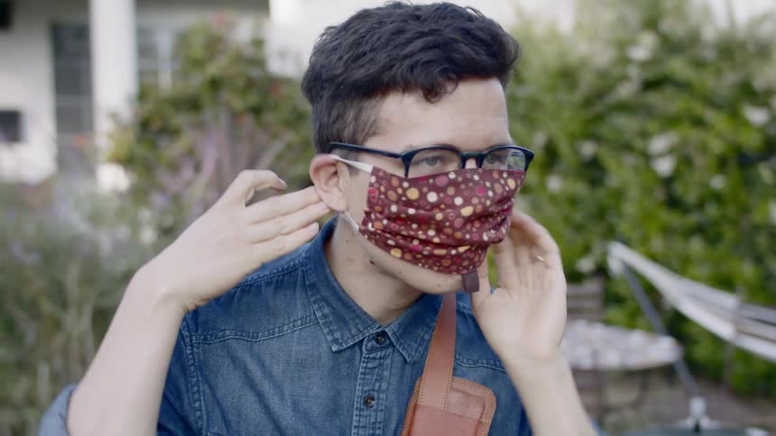 Man puts on a patterned face mask continues to walk
