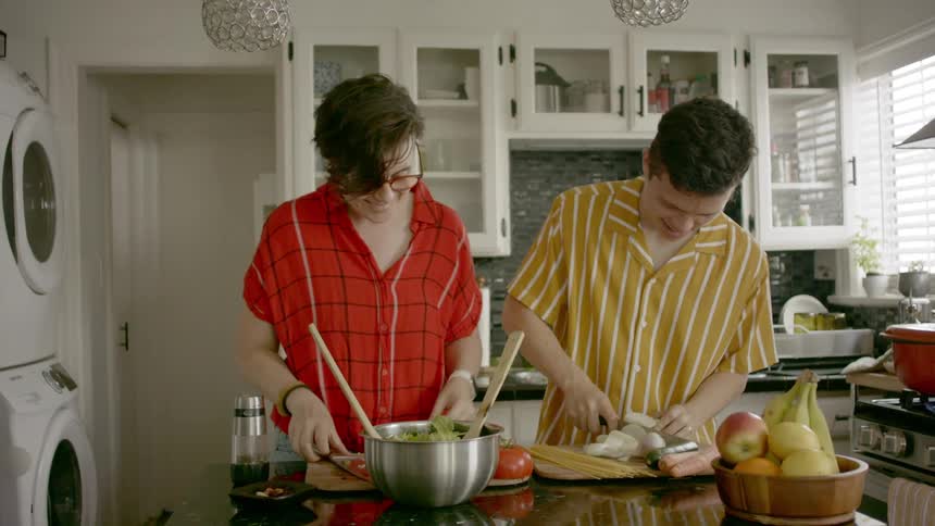 A woman and a man chatting while preparing food together in a kitchen